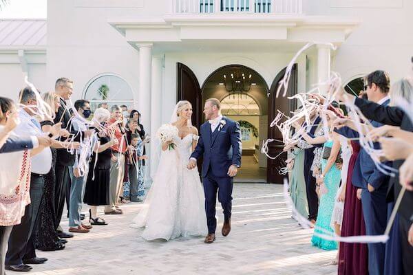 bride and groom's exit wedding with wedding guests waiving ribbon wands