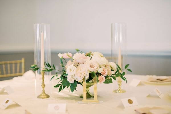 pink and white centerpiece with gold table numbers and taper candles