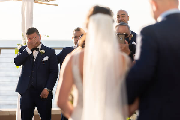 Groom bursts into tears as he sees his bride walking down the aisle during their Opal Sands outdoor wedding ceremony