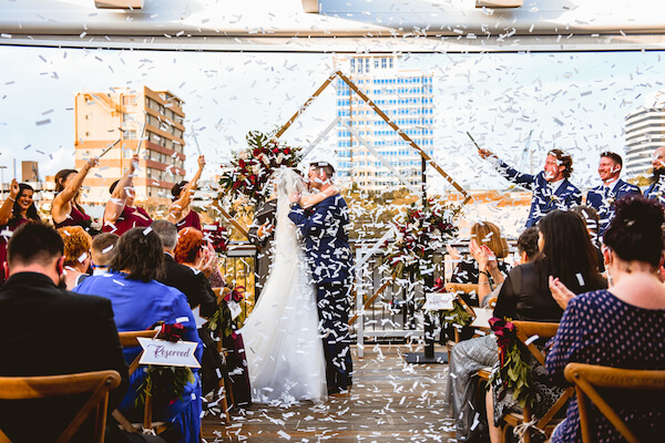 bride and groom sealing their wedding vows with a kiss in an exploding of Flutter Fetti