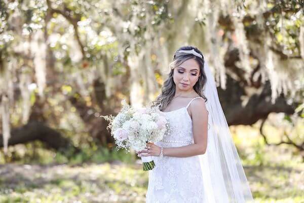 bride in beautiful lace wedding gown with a soft white and pink bridal bouquet