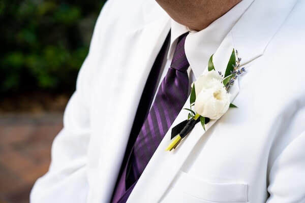 groom wearing a frilly white tulip boutonniere