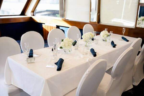 table with white linen, white chair covers and blue napkins on the Yacht StarShip