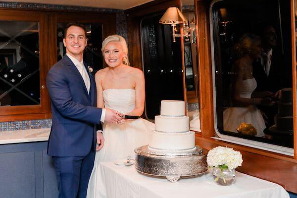 bride and groom cutting their three tiered white wedding cake by A Piece of Cake and Desserts in Tampa