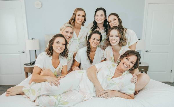 bride and bridal party posing on the bed before getting ready