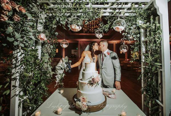 bride and groom kissing next to their wedding cake