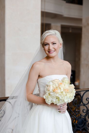 beautiful bride in a strapless wedding gown holding white and peach bridal bouquet