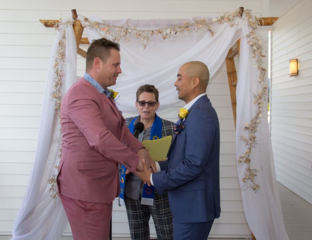 two grooms holding hands as they exchange their wedding vows