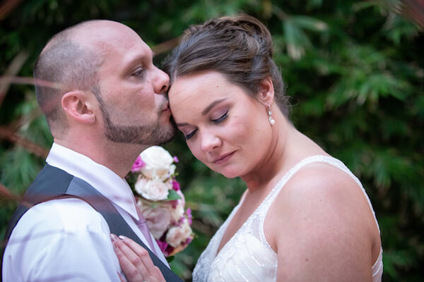 groom leaning in to kiss his brides forehead