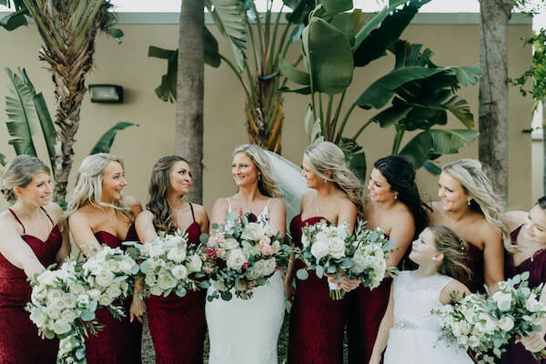 bridesmaids in burgundy dresses posing for photos with st Pete beach bride