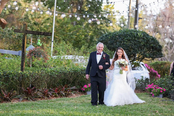 bride walking across the lawn with her father 