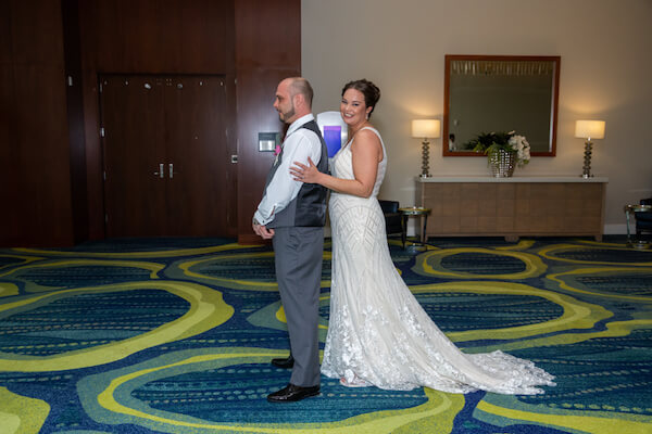 bride standing behind her groom just before he turns around for their first look