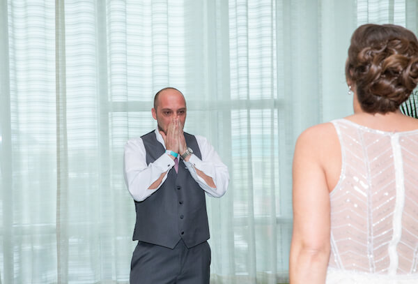 groom holding back tears after seeing his bride for the first time