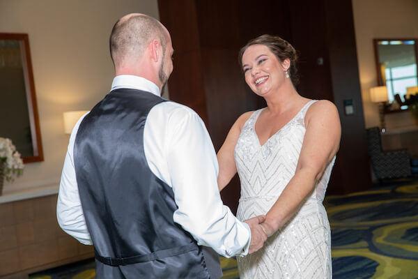 smiling bride holding her grooms hands after their first look