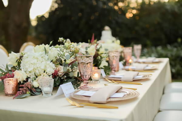 intimate backyard wedding reception with pink glass chargers, vintage pink glassware and gold flatware 