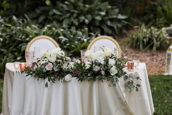 crescent shaped sweetheart table dressed in white and rose gold