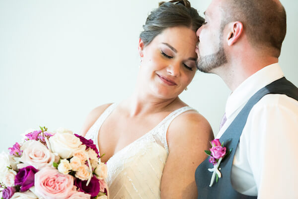 groom kissing his bride's forehead