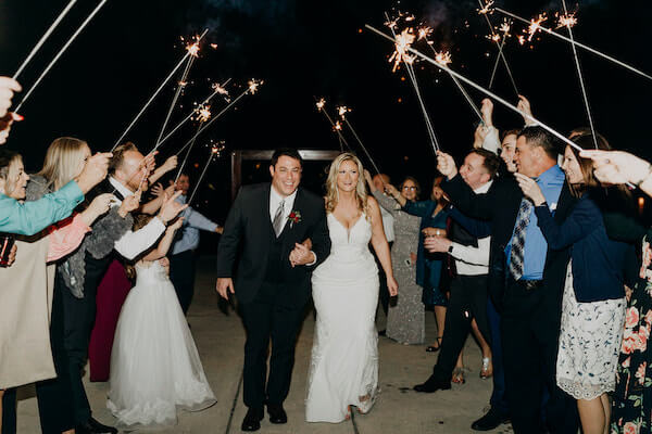 Newlywed bride and groom exiting under an arch of sparklers