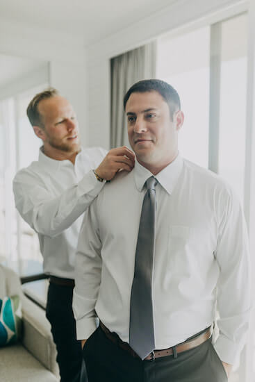 best man helping fix the groom's shirt and tie