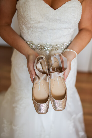 bride holding her rose gold ballet slippers