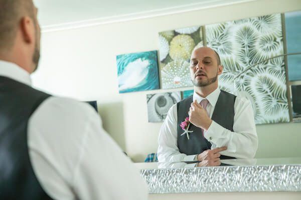 groom standing in front of the mirror checking his cufflinks