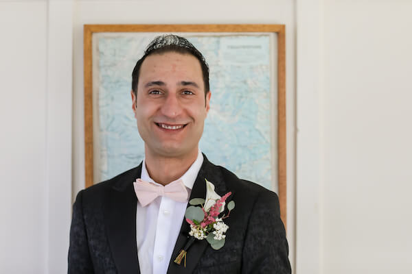 groom wearing a pink bow tie on his wedding dayposing for photos