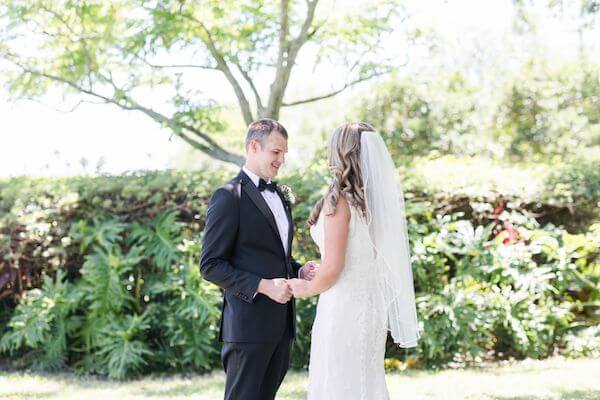 bride and groom standing in a garden after their first look