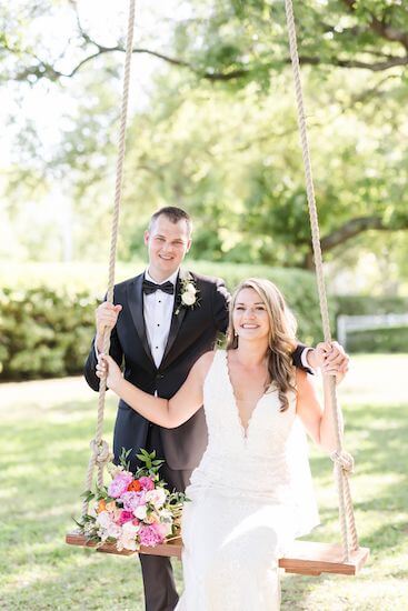 groom pushing his bride on a swing in a garden