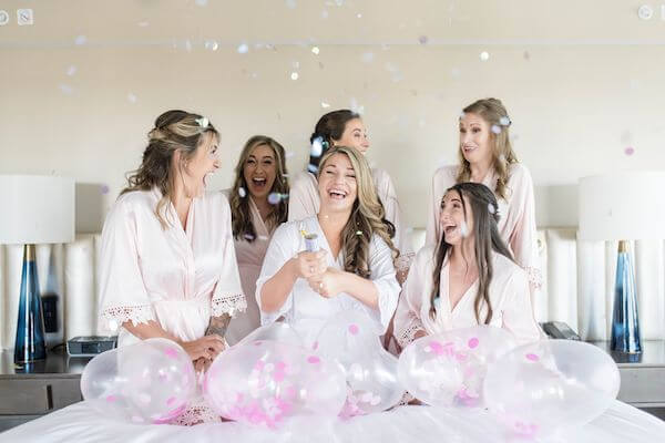 bride and brill party popping confetti surrounded by balloons