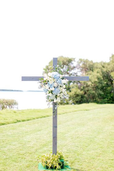 a rustic Woden cross dressed with blue and white flowers at a Tampa Bay Watch wedding