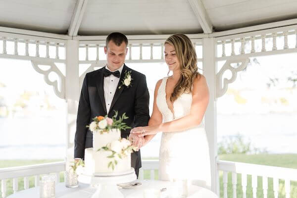 bride and groom cutting their wedding cake in a garden gazebo