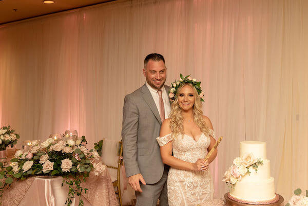 bride and groom posing to cut their wedding cake at the sand pearl resort on clearwater beach