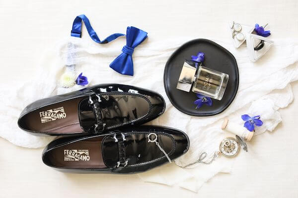 flat lay photo of a groom's wedding day accessories including his Ferragamo shoes