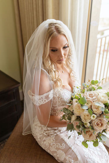 bride wearing a boho style lace wedding gown with loose pink and antique white bouquet