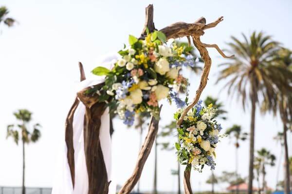 part of a driftwood wedding arch decorated with fabric and colorful flowers