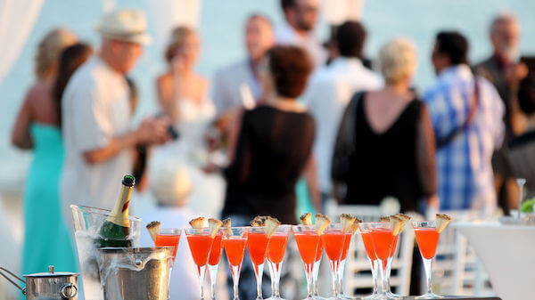 Guests gathered around outdoors during a cocktail party style wedding reception with signature cocktails on a table