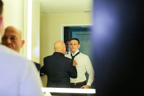 father of the groom helping his son with his tie