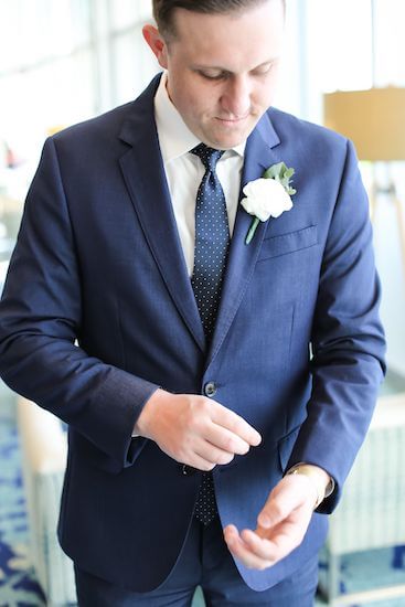 groom in a blue suit fixing his watch