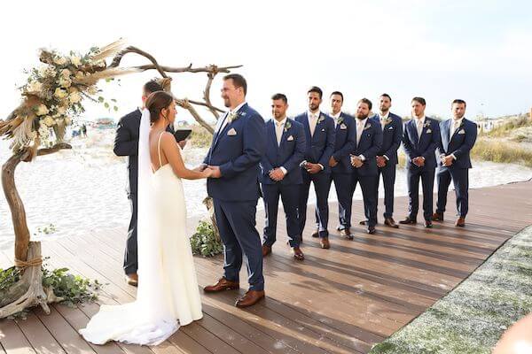 bride and groom exchanging wedding vows in front of a driftwood wedding structure