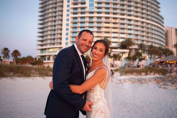 newlywed couple on Clearwater Beach with the Opal Sands Resort behind them