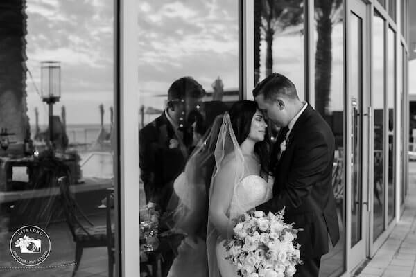 black and white photo of bride and groom leaning on glass doors