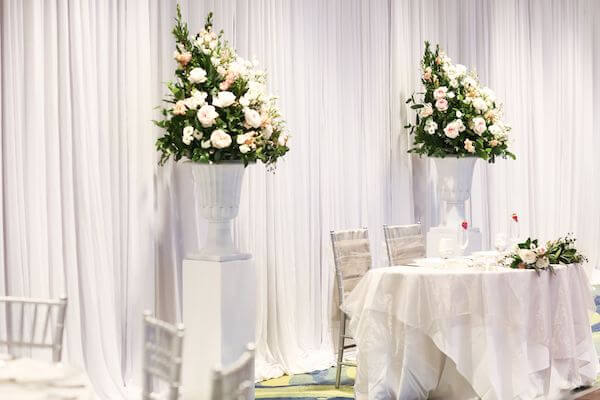 sweetheart table flanked by floral pieces repurposed from the ceremony