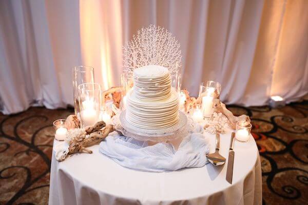 unique wedding cake surrounded by coral, shells and driftwood