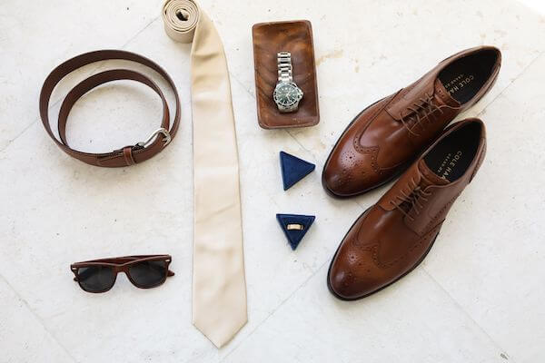 flat lay of groom's wedding accessories in browns and neutral tones