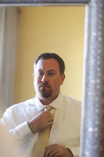 groom looking in the mirror fixing his tie