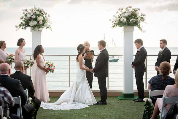 bride and groom exchanging wedding vows as a sailboat floats by off of Clearwater Beach