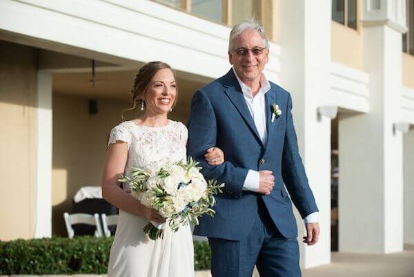 bride to be smiling ear to ear as her father walks her down the aisle