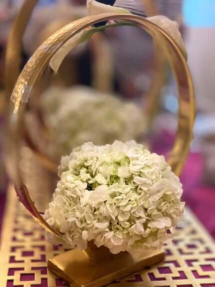 wedding centerpiece with gold rings and white hydrangea