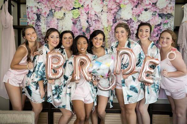 bride and bridal party posing in custom robes with fun 'bride' balloons