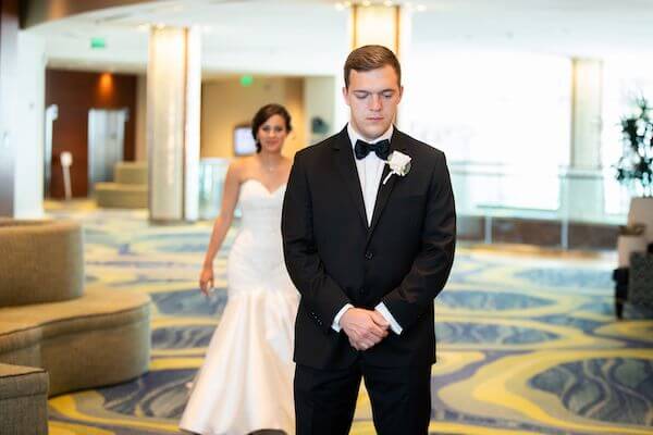 Clearwater Beach bride walking up behind her groom for their first look 